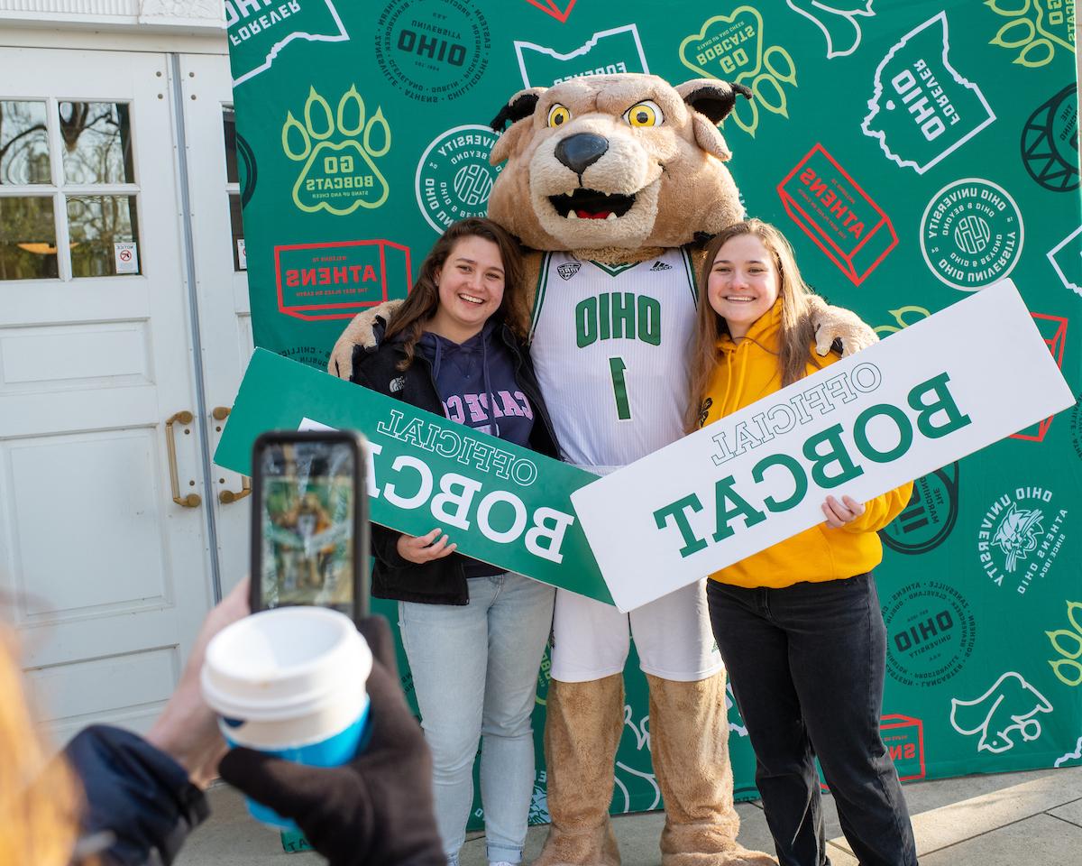 Two students holding up "I'm a Bobcat!" signs with Rufus
