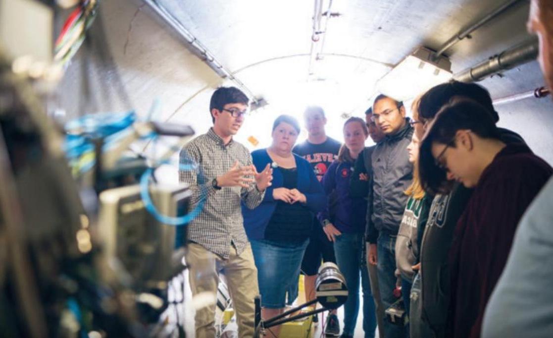 Dr. 扎克·梅塞尔和学生们在爱德华兹加速器实验室的飞行时间隧道里, 位于校园内.